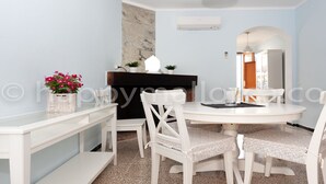 A dining area with a round table, white chairs, a small side table, a dark wooden cabinet, and a marble accent wall. - 3 bedrooms ground floor, large terrace and pool, near the beach. (Can Picafort)