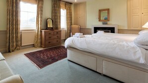 A hotel bedroom with a large bed, a dresser, a mirror, a fireplace, and a view of the outdoors through the window. - 4 bedroom accommodation in Market, Clarence & Sandquay (Market, Clarence & Sandquay)