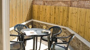 A patio with a table and chairs, two glasses of wine, and a book. - 2 bedroom accommodation in Buckley St (Buckley St)
