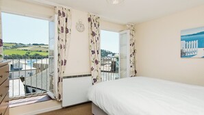 A bedroom with a bed, a dresser, a window with curtains, a clock, and a painting on the wall. - 2 bedroom accommodation in Buckley St (Buckley St)