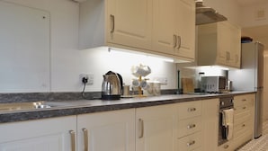 A modern kitchen with white cabinets, stainless steel appliances, and a granite countertop. - 3 bedroom accommodation in Troutbeck Bridge (Troutbeck Bridge)
