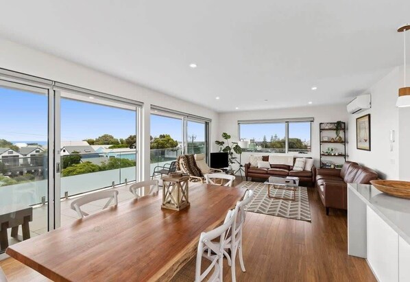 Enjoy expansive views of the surrounding area from the large windows in this stylish living space, featuring a dining table and comfortable seating area.