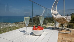 Une table avec deux flûtes à champagne et un saladier rempli de fraises, offrant une vue panoramique sur la côte.