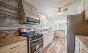 A modern kitchen with a gas stove, oven, microwave, and stainless steel refrigerator.