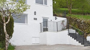 Un bâtiment blanc à deux étages, avec un escalier en métal noir menant à un balcon.