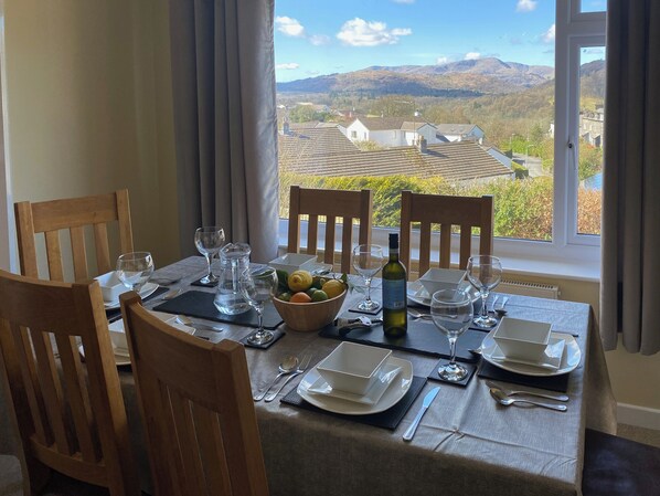 A dining table set for four with a view of mountains through a window. - 3 bedroom accommodation in Ambleside (Ambleside)