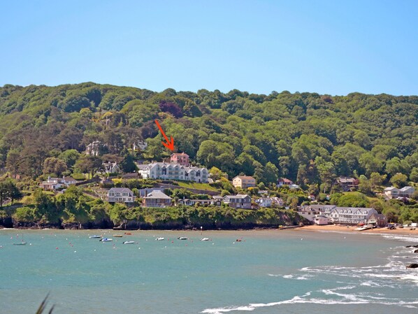 A coastal town with houses on a hillside, a beach, and boats in the water.