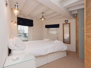 A bedroom with a bed, bedside table, and a window with a view. - 1 bedroom accommodation in Fore St (Fore St)