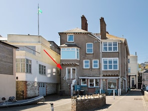 A multi-story building with a visible ground-floor shop, a flag on a pole, and a boat tied to the building.
