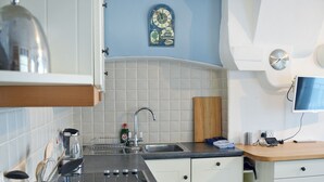 A kitchen with a stove, sink, and a clock on the wall.