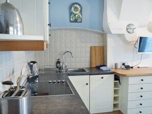A kitchen with a stove, sink, and a clock on the wall.