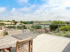 Un balcón con vista a un río, casas y colinas verdes.