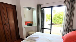 Ein Hotelzimmer mit einem Bett, einem Kleiderschrank, einem Spiegel und einem Fenster mit Vorhängen.