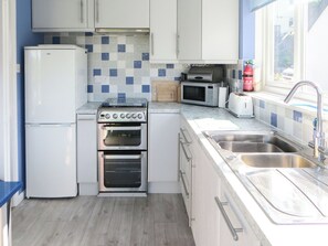 Una cocina compacta con horno integrado, microondas y refrigerador.