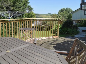 A wooden deck with a metal railing, a small table, and a chair. - 3 bedroom accommodation in Salcombe (Salcombe)