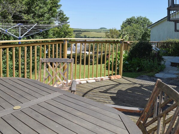 A wooden deck with a metal railing, a small table, and a chair.