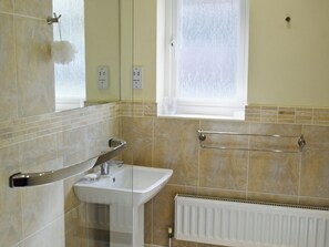 A bathroom with a sink, mirror, towel rack, and a window.