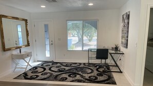 A modern living room with a large mirror, a desk, and a chair.