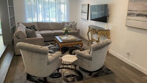 A living room with a sofa, two armchairs, a coffee table, and a TV.