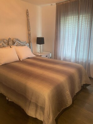 Una cama bien hecha con una colcha marrón, un cabecero decorativo y una mesita de noche con una lámpara.