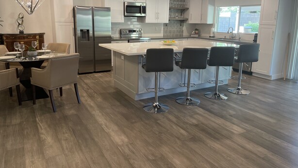 A modern kitchen with white cabinets, stainless steel appliances, and a central island with bar stools.