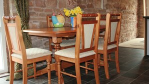 Une table de salle à manger en bois, accompagnée de quatre chaises, un vase rempli de fleurs jaunes et un objet décoratif en céramique.