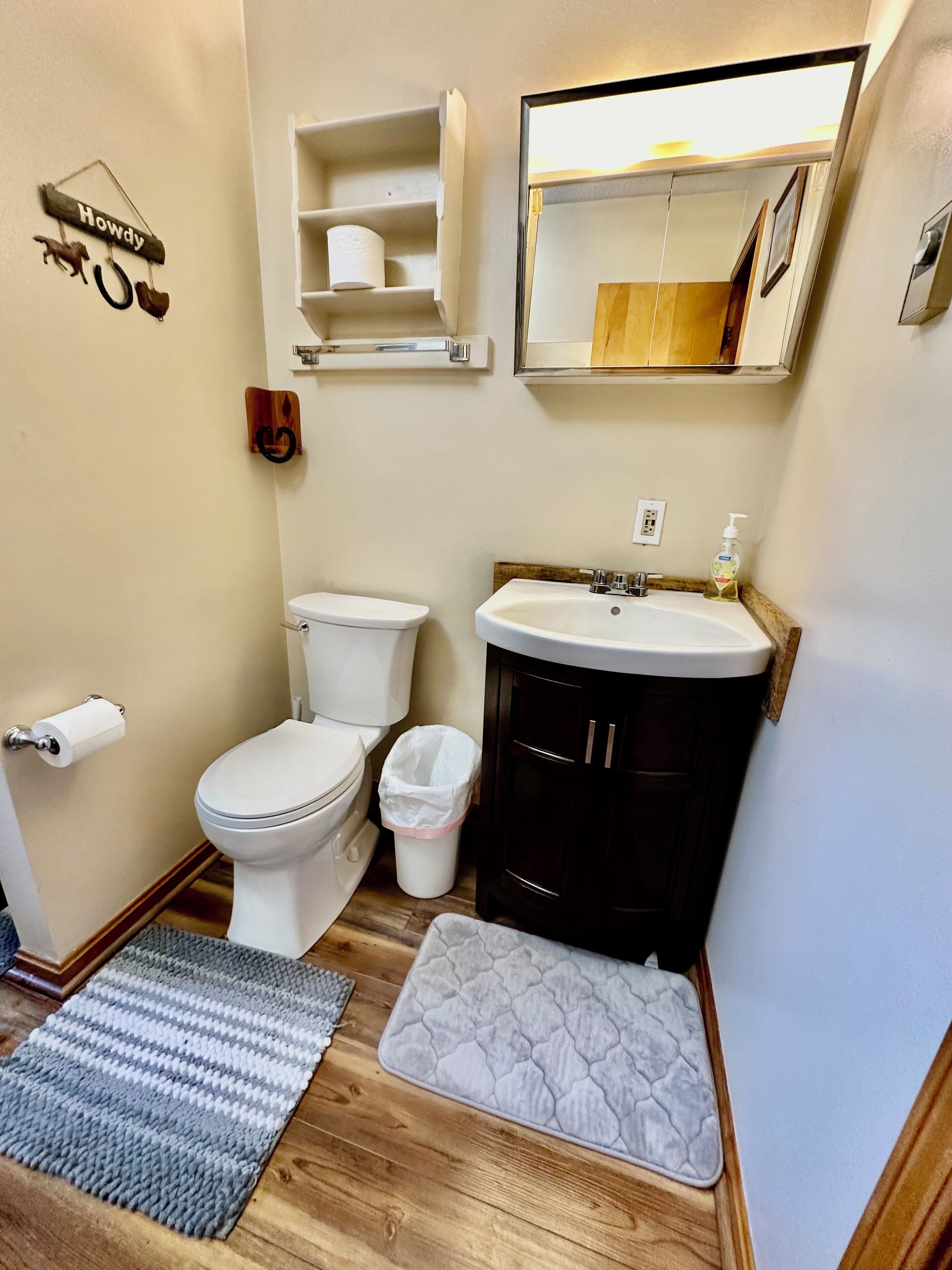 A compact bathroom with a toilet, sink, and storage shelves.