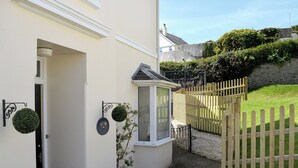 A narrow pathway leading to a house with a white exterior, a small window, and a wooden fence. - 5 bedroom accommodation in Devon Rd 2 (Devon Rd 2)