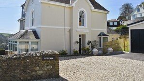 A two-story house with a stone wall in front, a gravel driveway, and a wooden fence. - 5 bedroom accommodation in Devon Rd 2 (Devon Rd 2)