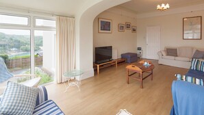 A spacious living room with a large TV, comfortable seating, and a view of a scenic outdoor area. - 5 bedroom accommodation in Devon Rd 2 (Devon Rd 2)