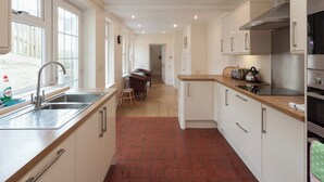 A modern kitchen with a central island, stainless steel appliances, and ample natural light from large windows. - 5 bedroom accommodation in Devon Rd 2 (Devon Rd 2)
