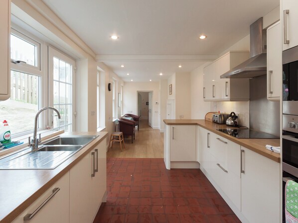 A modern kitchen with a central island, stainless steel appliances, and ample natural light from large windows.
