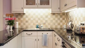 A kitchen with white cabinets, a sink, a stove, and a toaster. - 1 bedroom accommodation in Mount Boone (Mount Boone)