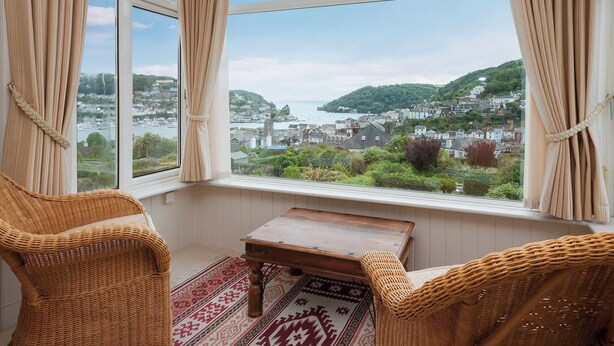 A room with a large window, wicker chairs, a small table, and a patterned rug. - 1 bedroom accommodation in Mount Boone (Mount Boone)