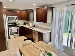 A modern kitchen with stainless steel appliances, wooden cabinets, and a dining area with a table and chairs. - Recline and Reset - Main Floor Bed/Bath w/lift chair, Edge of Mayo Campus (Rochester)