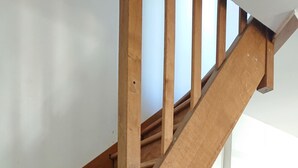 Eine Holztreppe mit Handlauf und einer verschlossenen Tür am Fußende.