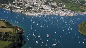 An aerial view of a coastal town with numerous boats in the harbor and a dense cluster of buildings along the shoreline. - This apartment is just a short walk from the centre of Salcombe. (Salcombe)