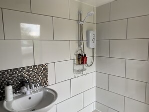 A bathroom with white tiles, a sink, a shower, and a soap dispenser. - Stunning 1-bed Star Gazing Bell Tent Loughborough (Loughborough)