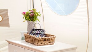 A white dresser with drawers, a wicker basket, a vase with flowers, and a mirror.