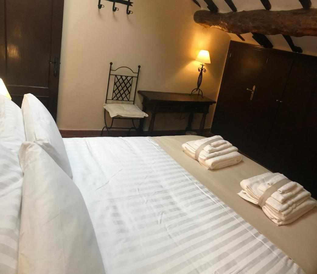 Un lit bien fait, avec du linge de lit et des serviettes blanches, une tête de lit en bois, une petite table avec une lampe et une armoire en bois foncé.
