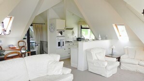 Un loft amplio con techo alto, muebles blancos, kitchenette y comedor con vistas.