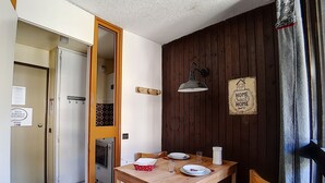 A dining area with a wooden table, chairs, and a mirror. There is a sign on the wall that says "HOME Sweet HOME." - travelski home classic - Résidence Origanes - Studio 2 personnes (Les Menuires)