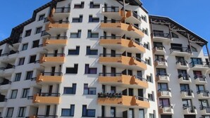 Ein mehrstöckiges Hotel mit Balkonen, einer flachen Dachterrasse und einem strahlend blauen Himmel.