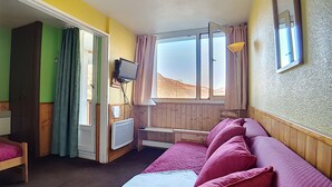 Ein Zimmer mit einem Bett, einem Schreibtisch, einem Sessel, einem Fernseher und einem Fenster mit Blick auf eine Wüstenlandschaft.