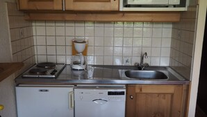 Eine kleine Küche mit Einbauherd, Kaffeemaschine, Spüle und Geschirrspüler.
