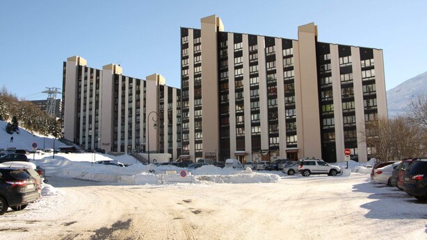A multi-story building with a modern architectural design, featuring a symmetrical facade with vertical lines and a mix of window patterns. - travelski home classic - Résidence Grande Masse - Studio 3 personnes 709 (Les Menuires)