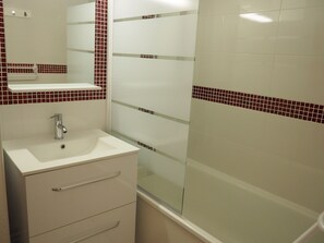 A bathroom with a white sink, mirror, and tiled walls.