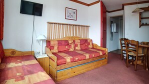 Ein Schlafzimmer mit einem hölzernen Bett, einem Schreibtisch, einem Stuhl, einem Fernseher und einem gerahmten Bild an der Wand.