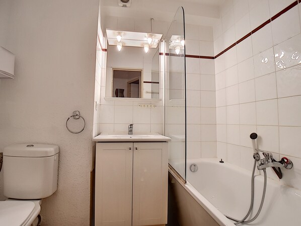Ein Badezimmer mit Toilette, Waschbecken, Spiegel und Badewanne.