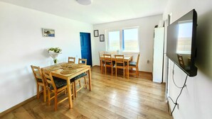 Un comedor con mesas y sillas de madera, una lámpara en el techo y vistas al exterior a través de ventanas.